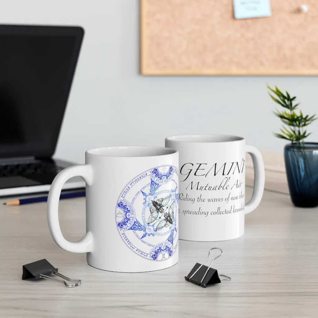 Two Gemini Zodiac Mugs on a desk, showing both the quote side and the elemental sigil side.