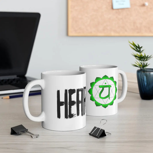 Two Heart Chakra Mugs on a desk, showing both the chakra symbol side and the "HEART" text side.
