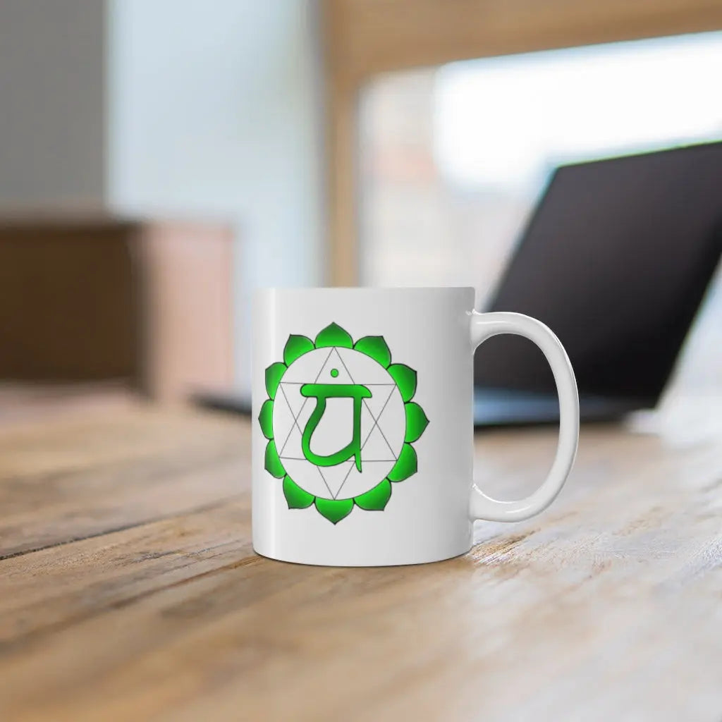 Heart Chakra Mug - Symbol side shown on a wooden desk with a laptop.