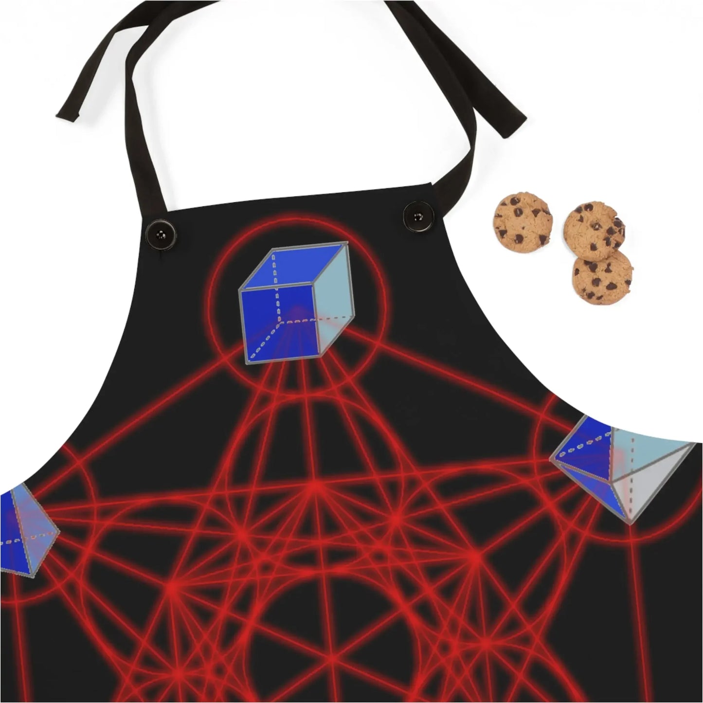 Black apron with red sacred geometry and blue 3D cubes, paired with chocolate chip cookies