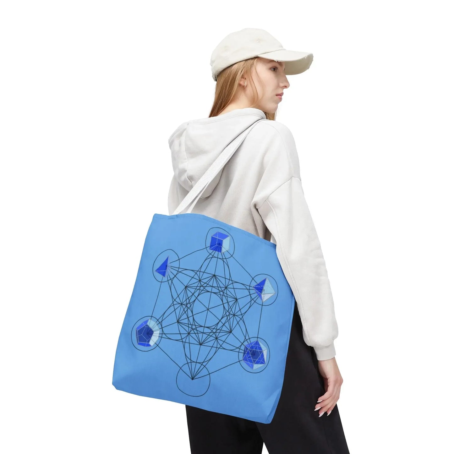 Blue tote bag with sacred geometry and chakra symbols, carried by woman in hoodie and cap