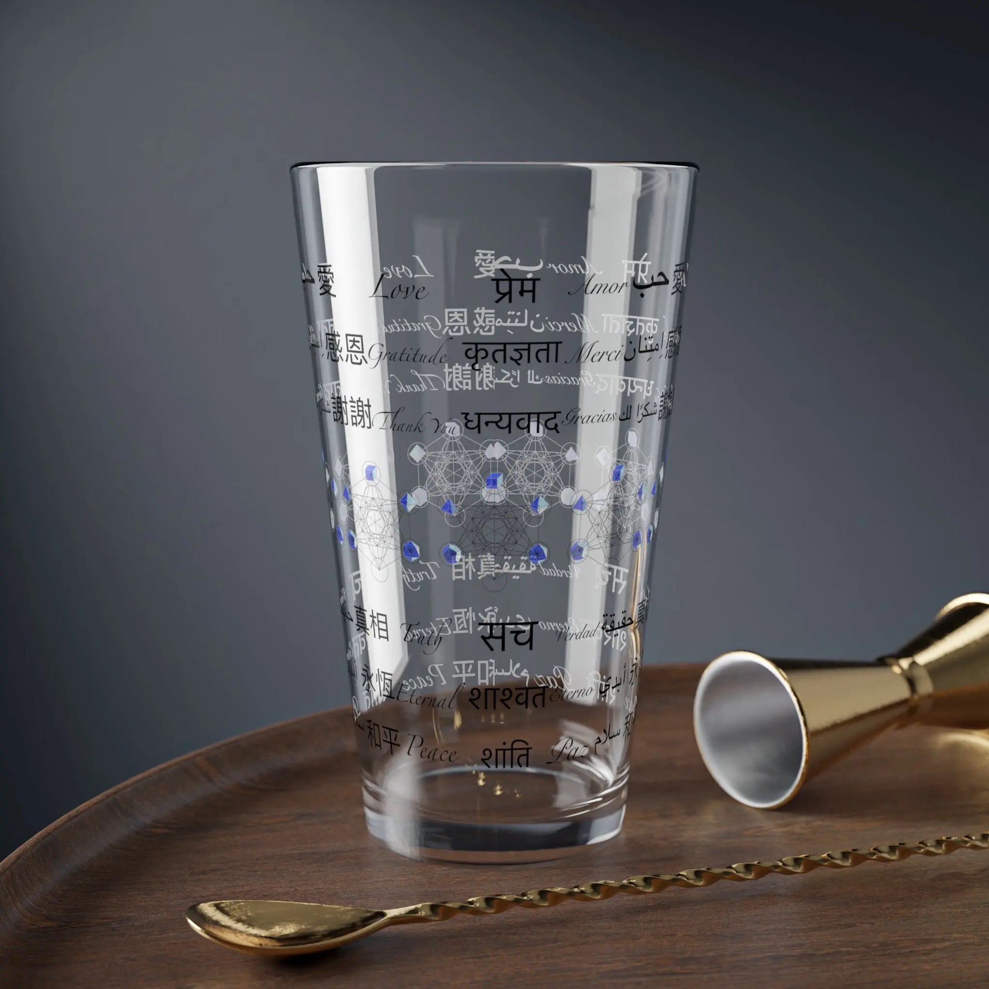 Power of Words Glass with sacred geometry in a lifestyle setting on a wooden table with bar tools.