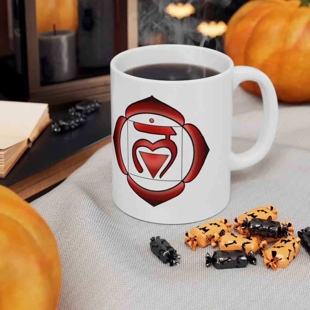 White mug with red heart chakra symbol, steaming coffee, Halloween candies, pumpkins, and journal nearby