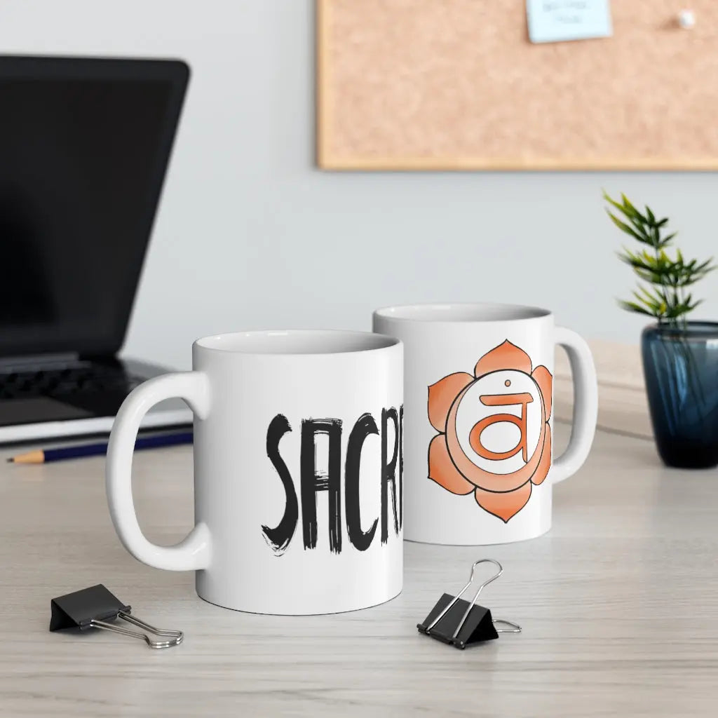 Two Sacral Chakra Mugs on a desk, showing both the "SACRAL" text side and the chakra symbol side.