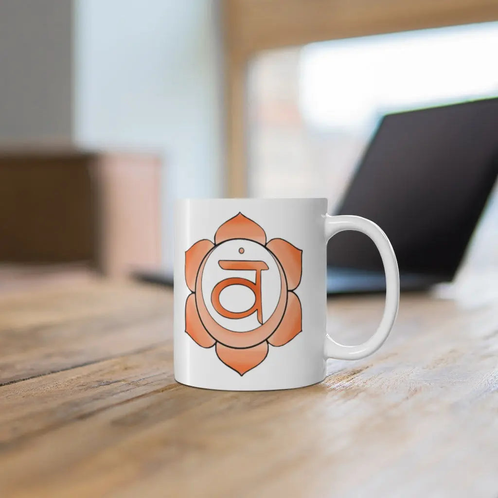 Sacral Chakra Mug - Symbol side shown on a wooden desk with a laptop.