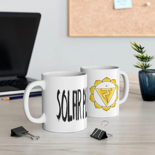Two Solar Plexus Chakra Mugs on a desk, showing both the chakra symbol side and the "SOLAR PLEXUS" text side.