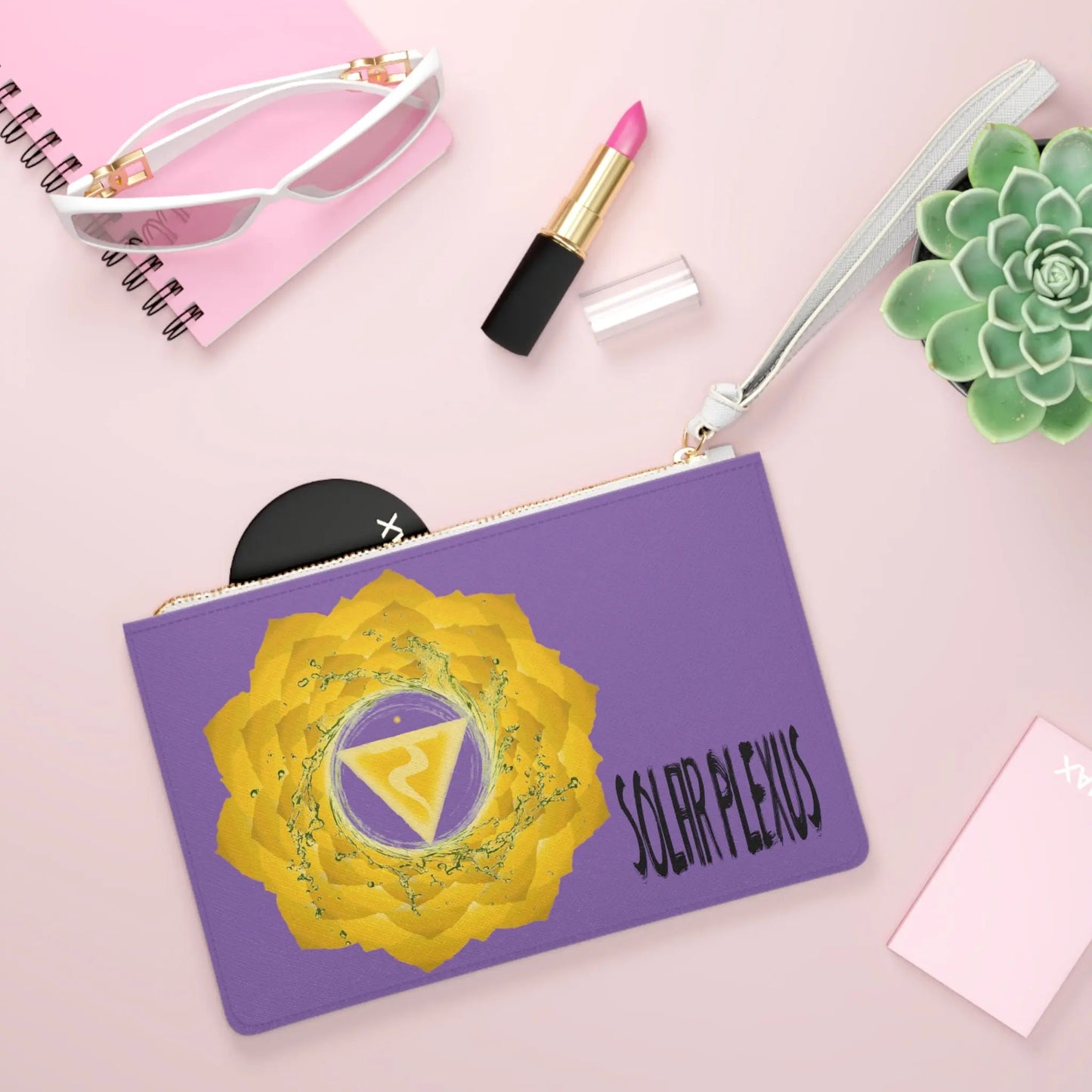 Solar Plexus Chakra Clutch shown in a lifestyle setting with sunglasses and lipstick on a pink background.