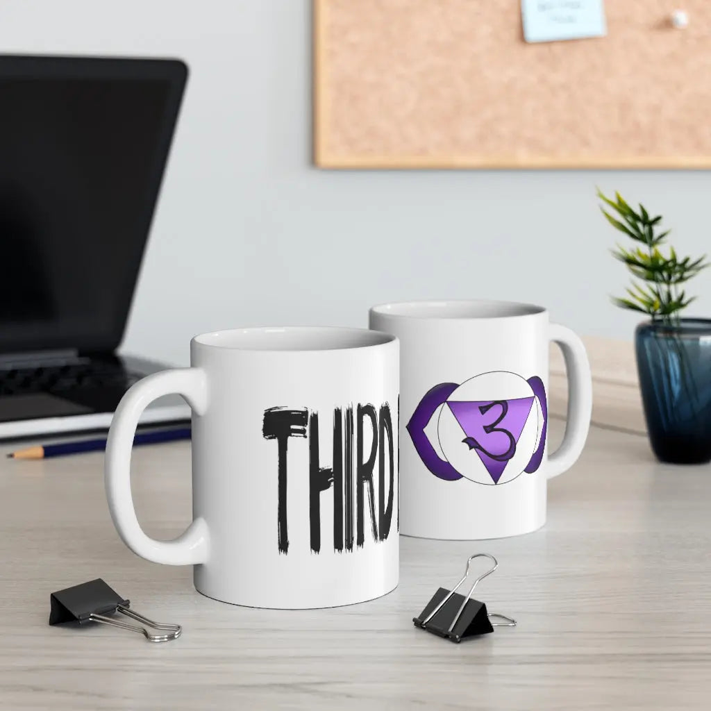 Two Third Eye Chakra Mugs on a desk, showing both the chakra symbol side and the "THIRD EYE" text side.