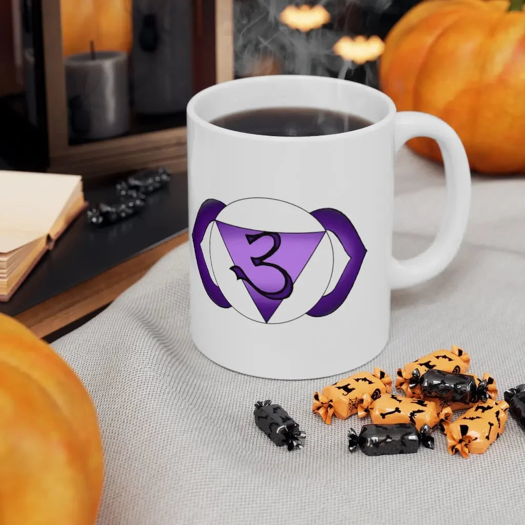 White mug with purple third eye chakra symbol, steaming coffee, Halloween candies, pumpkins