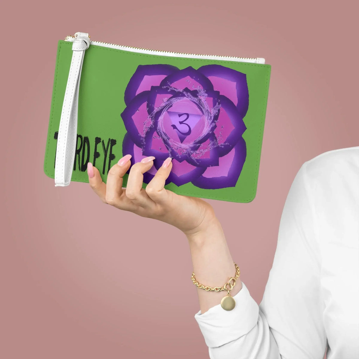 Green wristlet pouch with purple Third Eye chakra symbol and 'THIRD EYE' text, held by hand with pink nails.