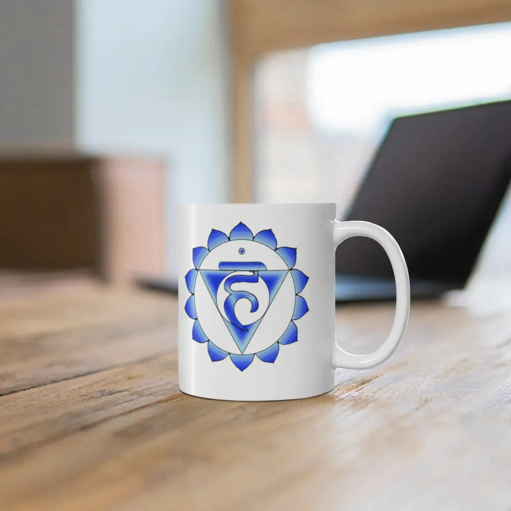 Throat Chakra Mug - Symbol side shown on a wooden desk with a laptop.