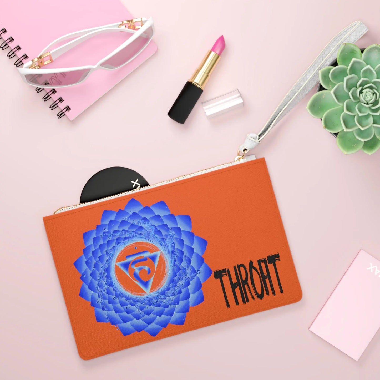 Throat Chakra Clutch shown in a lifestyle setting with sunglasses and lipstick on a pink background.