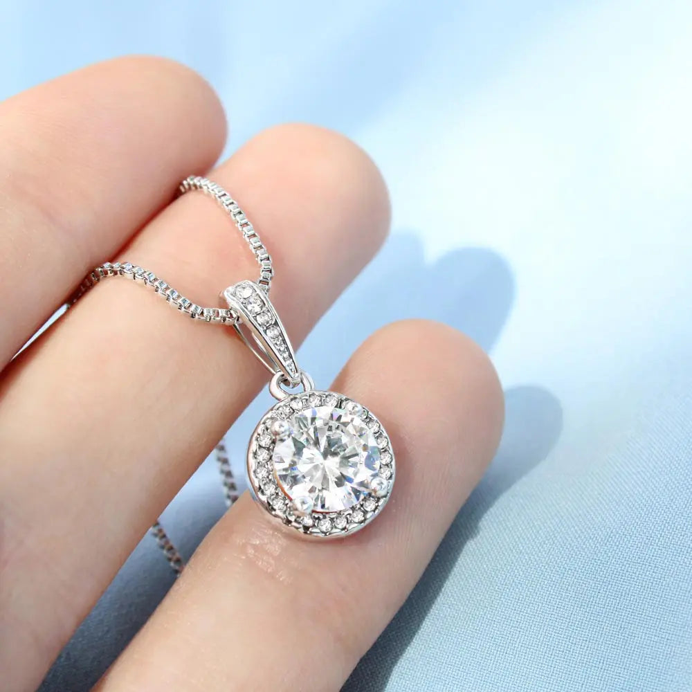 Hand holding the Timeless Brilliance necklace to show its detail and shine.
