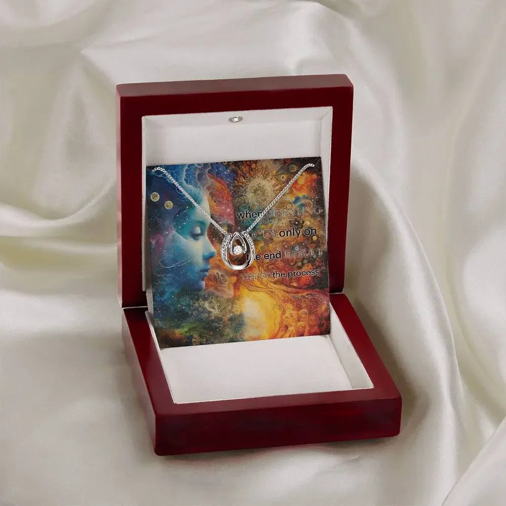 The luxury gift box for the "Trust the Process" necklace resting on white silk.