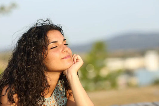 Woman with curly hair meditating outdoors, embracing mindfulness and inner peace for chakra balance